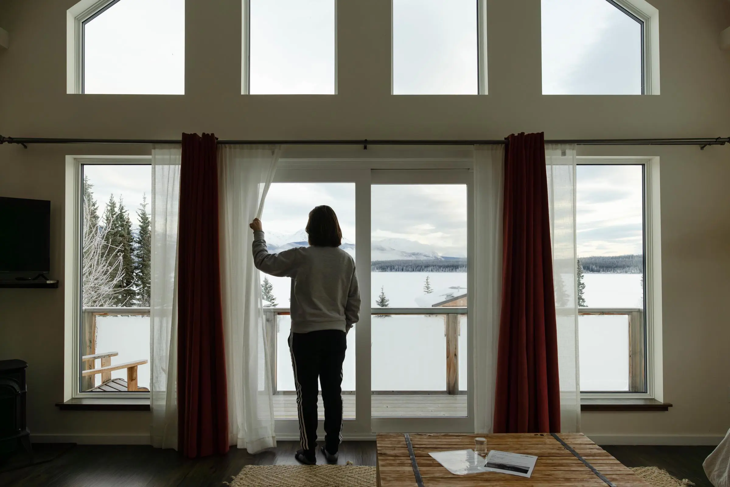 Person opening the curtains to look out at the snowy landscape.